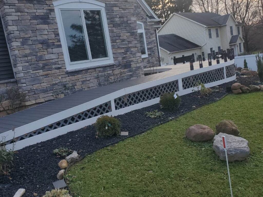 Stone house with an accessible ramp leading to a deck with white lattice skirting in Rochester, NY.