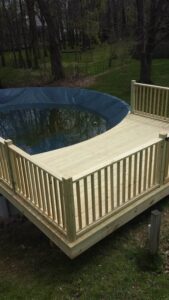 Newly built wooden deck surrounding an above-ground pool in a backyard in Rochester, NY.