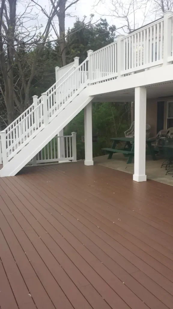 Multi-level composite deck in Rochester, NY, with rich brown decking, white railings, and under-deck patio space.