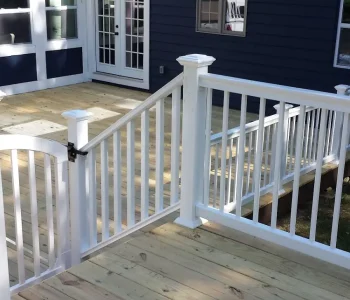 Newly constructed wooden deck with white vinyl railings and a safety gate in Rochester, NY.