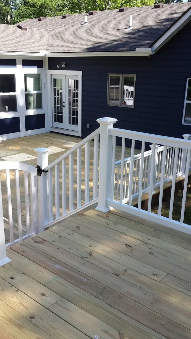 Newly constructed wooden deck with white vinyl railings and a safety gate in Rochester, NY.