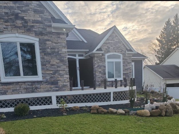 Stone-front house with a covered porch and white lattice skirting in Rochester, NY.